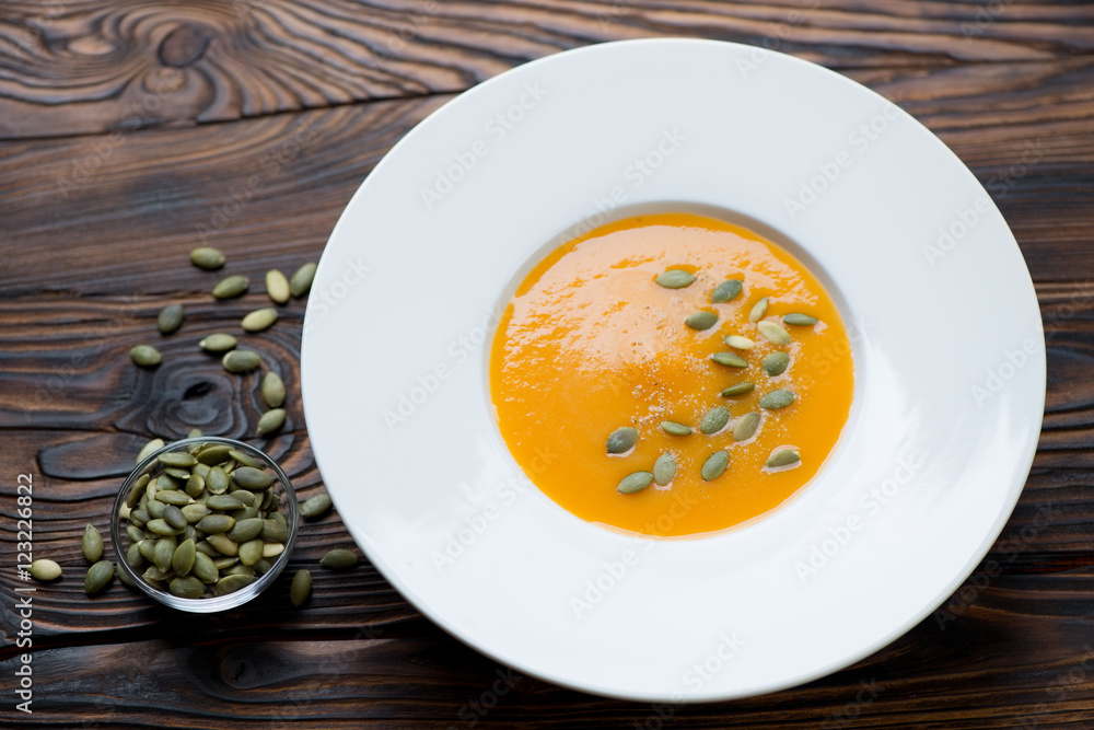 Glass plate with pumpkin cream-soup, studio shot Glass plate with pumpkin cream-soup, studio shot