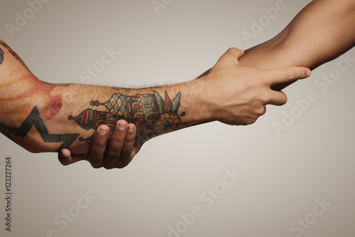 Close up of a forearm Roman, Civil war handshake of two young men, one with tattoos, on white background photo