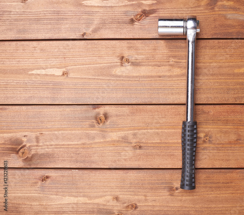 Socket metal wrench with black handle on wooden surface