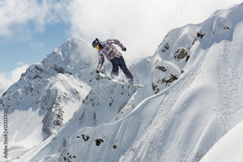 Flying snowboarder on mountains. Extreme sport.