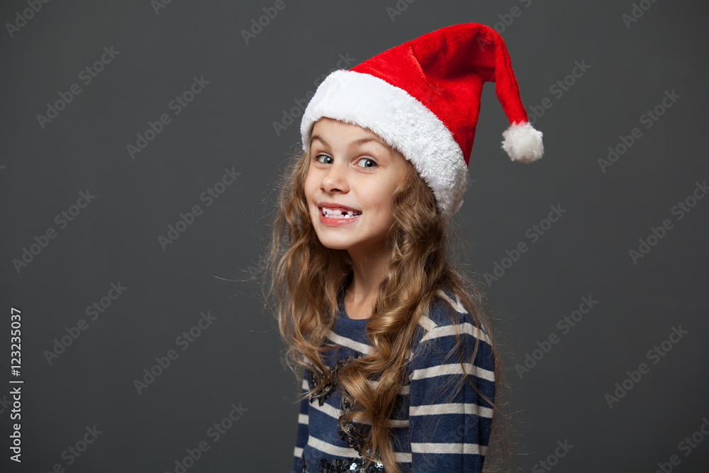 Profile portrait of a cute little girl in a christmas cap, gray background Profile portrait of a cute little girl in a christmas cap, gray background