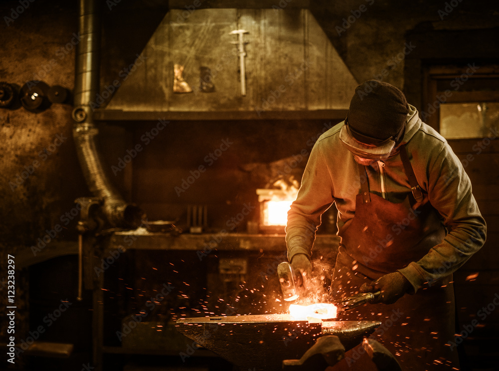 Αυτοκόλλητο The blacksmith forging the molten metal on the anvil in smithy