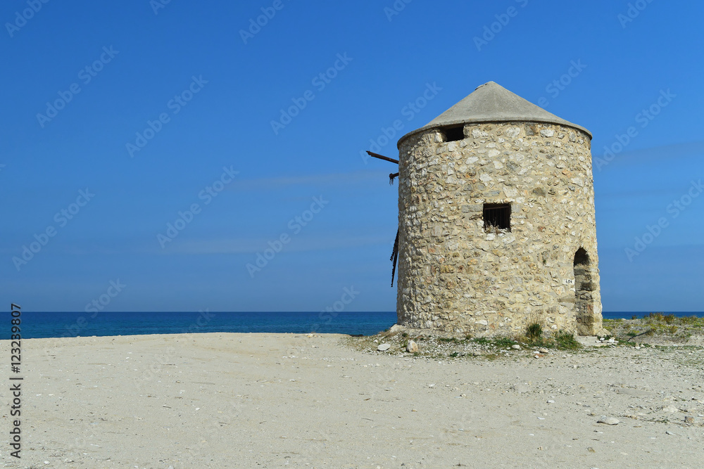 Old abandoned stone-built windmill on the beach of Lefkada, Greece