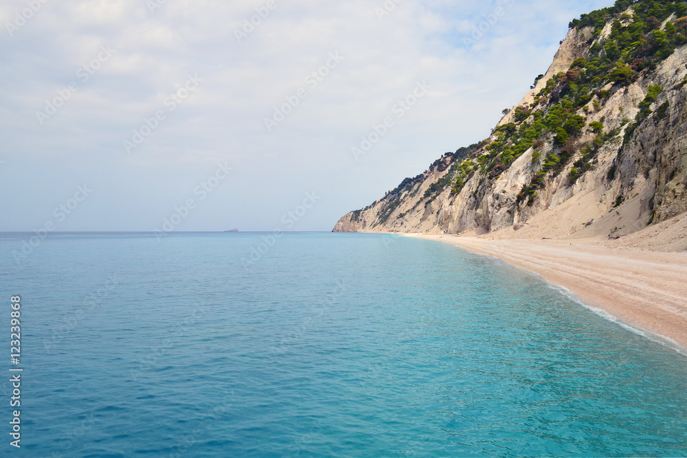 Steep rocky hills falling to secluded beach and calm turquoise sea