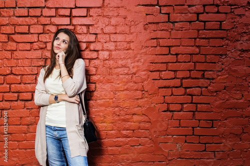 Young beautiful happy woman in casual cloths against brick wall