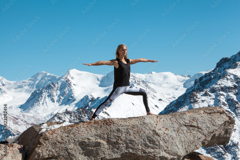 Woman is practicing yoga against Kazakhstan mountains.