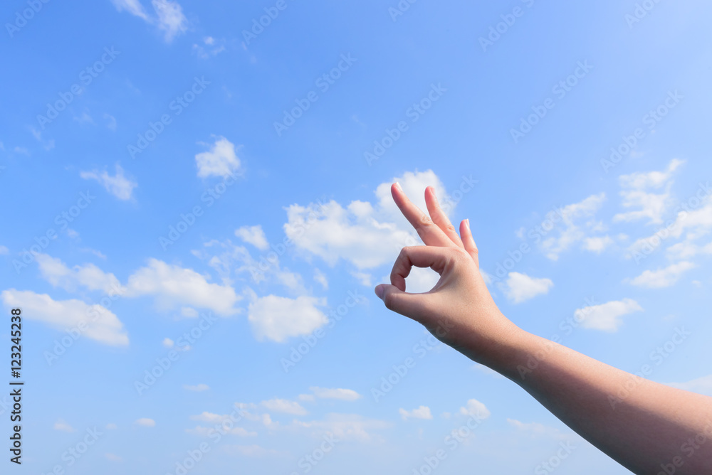 Man's hand showing an Okay sign blue sky and clouds background Man's hand showing an Okay sign blue sky and clouds background