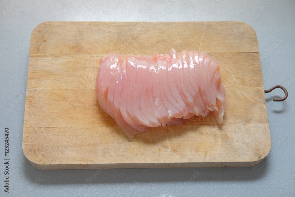 Raw chicken breast without skin on on the kitchen wooden board.