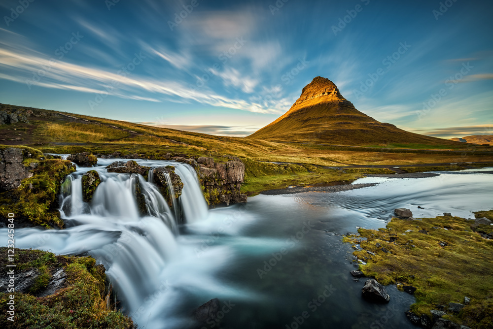 Fototapeta premium Summer sunset over the famous Kirkjufellsfoss Waterfall with Kirkjufell mountain in the background in Iceland. Long exposure.