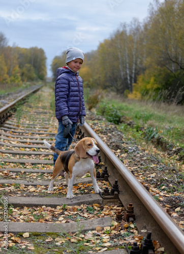 Мальчик семи лет на прогулке осенью в лесу с собакой породы бигль 