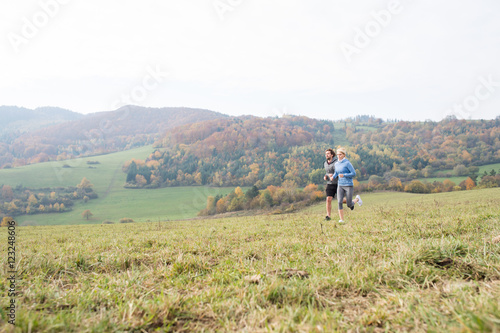 Beautiful young couple running in sunny autumn nature. © Halfpoint