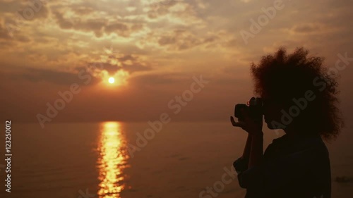 Beautiful female phorograph taking picture of sunrise at sea Slow motion photo
