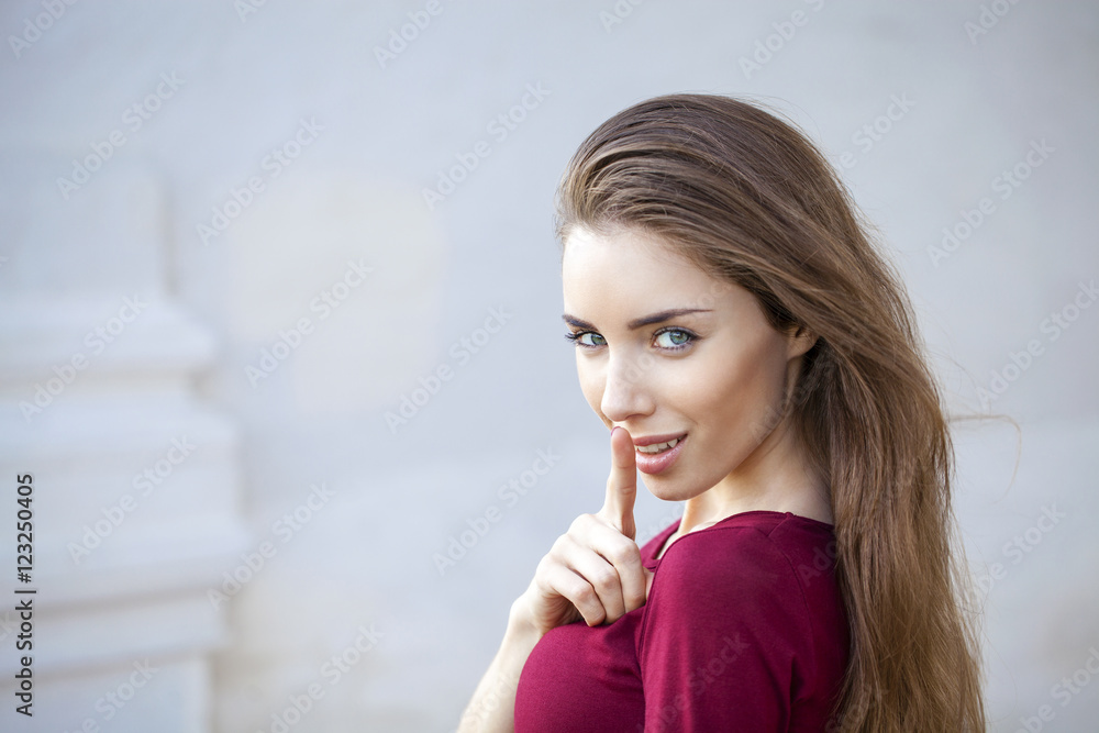Young beautiful brunette woman has put forefinger to lips as sig Young beautiful brunette woman has put forefinger to lips as sig