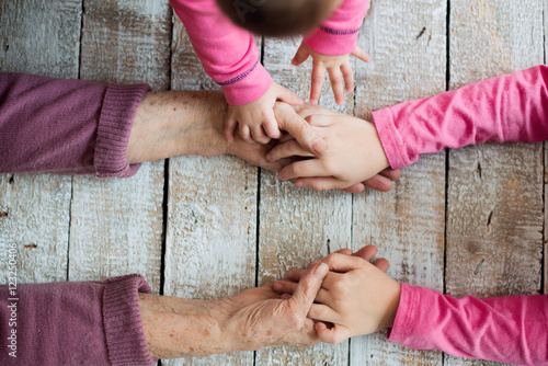 Hands of unrecognizable grandmother and her granddaughters