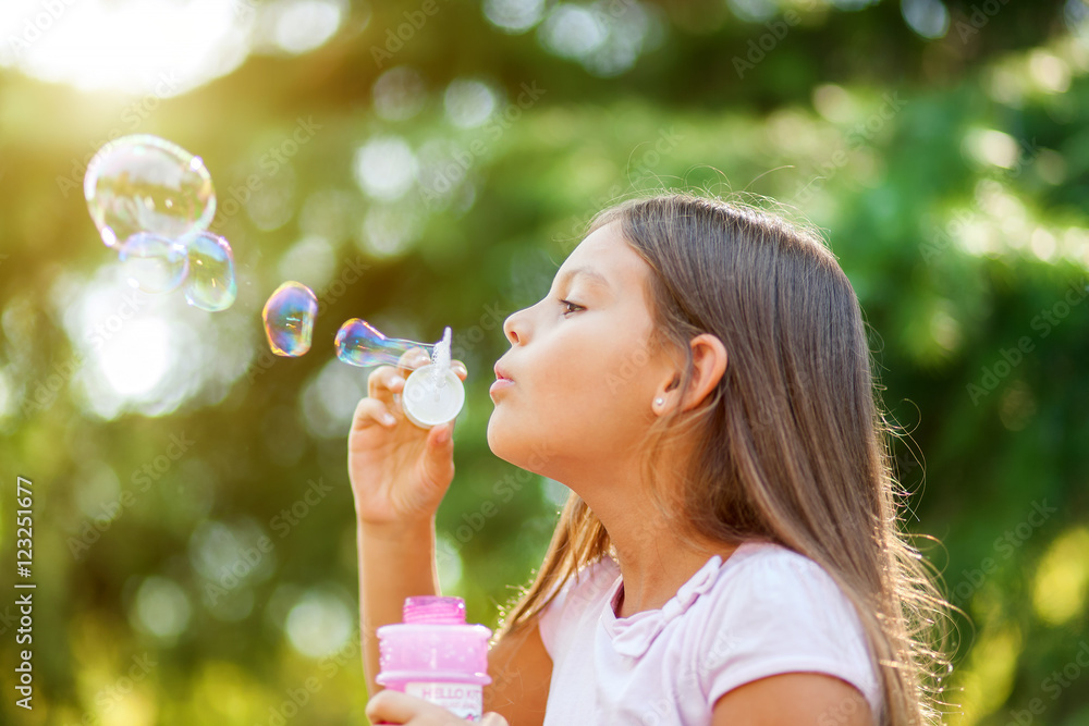 Children girl blowing soap bubbles in outdoor forest Children girl blowing soap bubbles in outdoor forest