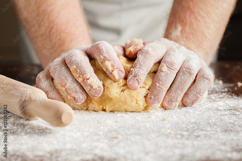 Making dough by men hands on wooden table background