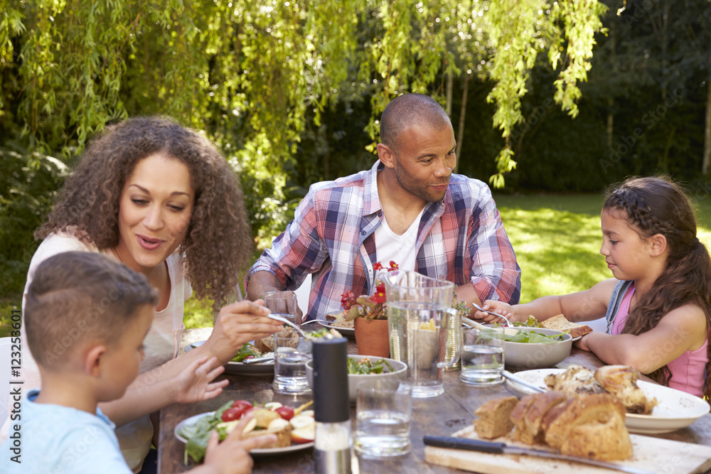 Family At Home Eating Outdoor Meal In Garden Together Family At Home Eating Outdoor Meal In Garden Together