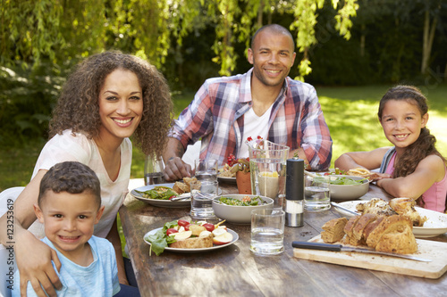 Portrait Of Family At Home Eating Outdoor Meal In Garden