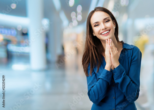 Happy gesturing smiling young woman, at shopping centre photo