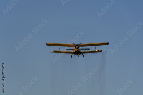 Crop duster spraying crops from the air in the morning light.