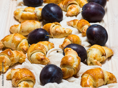 Croissant Cookies with Jam and plums arround. Roll up. photo