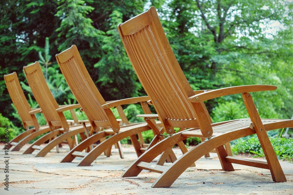 Empty patio with wood chairs lined up and ready for sunbathers a