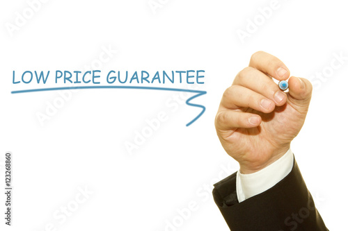 Hand writing "Low price guarantee" with a marker on a transparent wipe board.