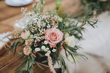 The composition of flowers and greenery is on a festive table in the area of wedding party