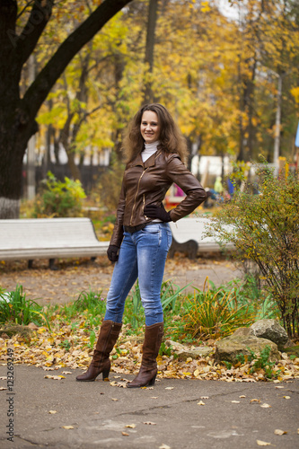 Autumn fashion image of young woman walking in the park