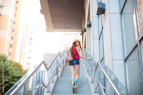 Beautiful young girl walking by steps in a city background © Buyanskyy Production