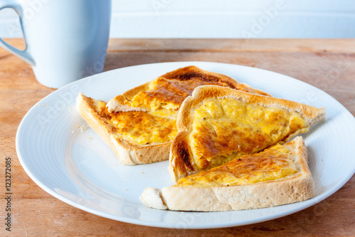 Foto Slices of welsh rarebit, a type of cheese on toast, on a white plate with a blue