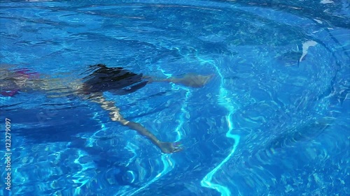 Woman swimming across the pool underwater.