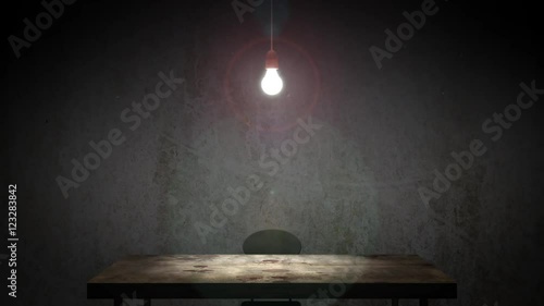 A classic old interrogation room with swinging incandescent bulb. The camera slowly zooms in to scene to enhance the eerie atmosphere. photo