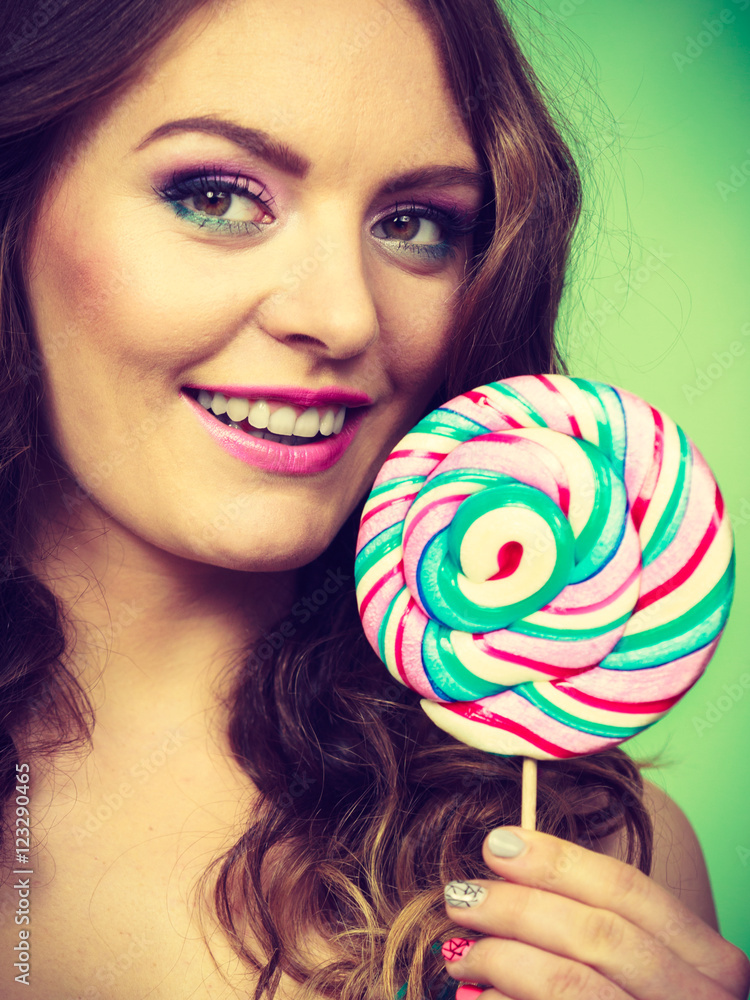 Smiling girl with lollipop candy on green