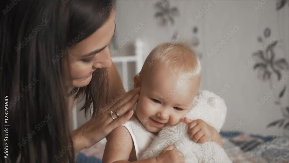 Young beautiful woman hugging her cute daughter with toy in berroom - motherhood concept Young beautiful woman hugging her cute daughter with toy in berroom - motherhood concept