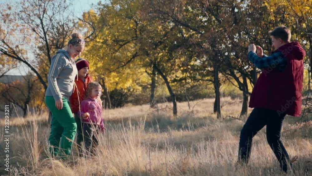 Slowmotion of family of 4 making photo in autumn park using a smartphone. Slowmotion of family of 4 making photo in autumn park using a smartphone.