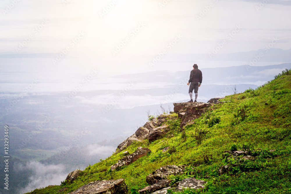 a man standing on the top of the mountain observing nature