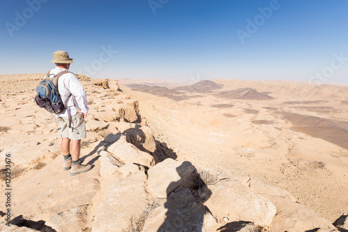 Man standing looking at desert crater moutains landscape.