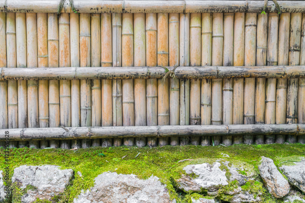 Bamboo fence on stone with green leaves . Bamboo fence on stone with green leaves .