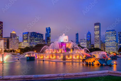 Chicago skyline panorama with skyscrapers and Buckingham fountain in Grant Park at night lit by colorful lights.