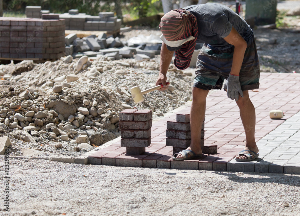 Worker puts sidewalk tile on the road Worker puts sidewalk tile on the road
