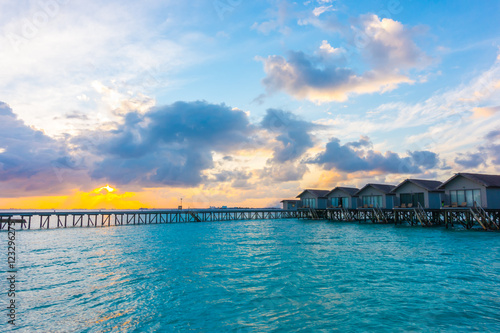 Beautiful sunrise with water villas in tropical Maldives islan