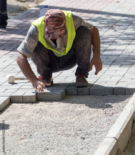 Worker puts sidewalk tile on the road