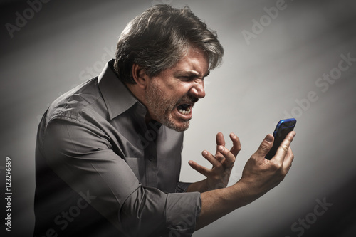 Φωτογραφία Angry screaming man with cell phone.