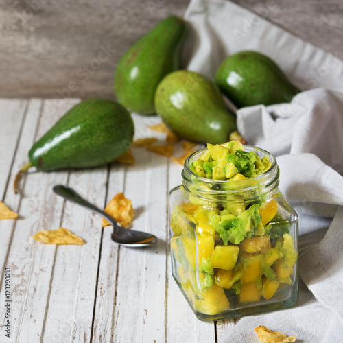 Homemade mango salsa with avocado on the rustic table. Mexican food. Vegetarian food concept.