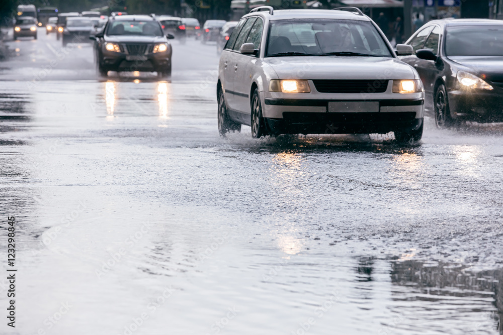 cars driving on a flooded city road with lights on during heavy rain cars driving on a flooded city road with lights on during heavy rain