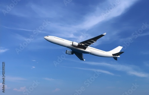 Passenger airplane flying under cloudy blue sky