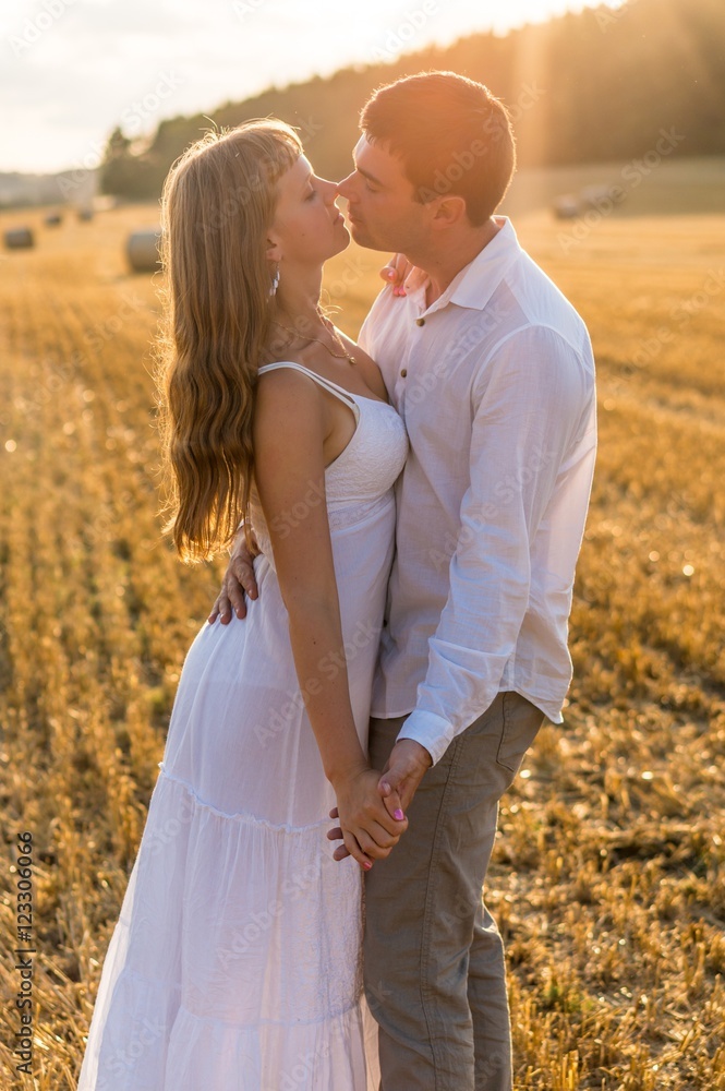 Young loving couple kissing in a field