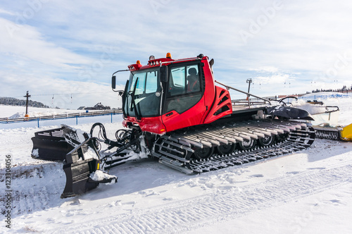 Red snow-grooming machine on snow
