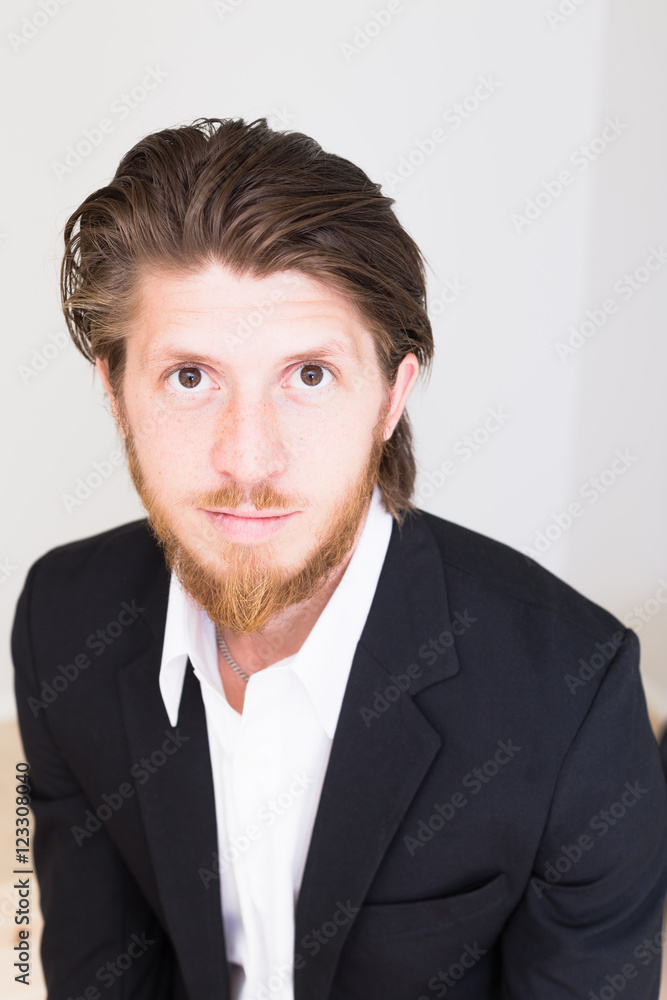 portrait of young scandinavian concentrated business man working on computer in office with plain light interior portrait of young scandinavian concentrated business man working on computer in office with plain light interior